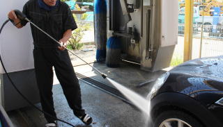 高圧洗浄機で車の洗車をしている男性